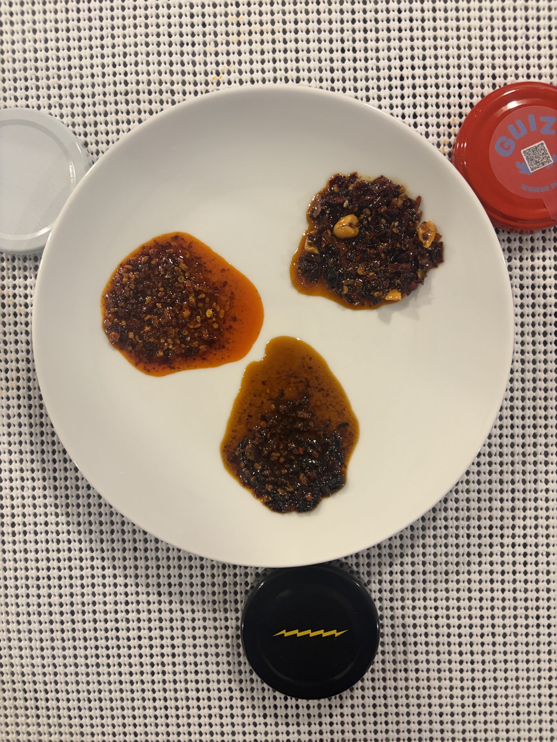Three original chili crisps spread on plate showing texture and color differences — Flavor Index Lab