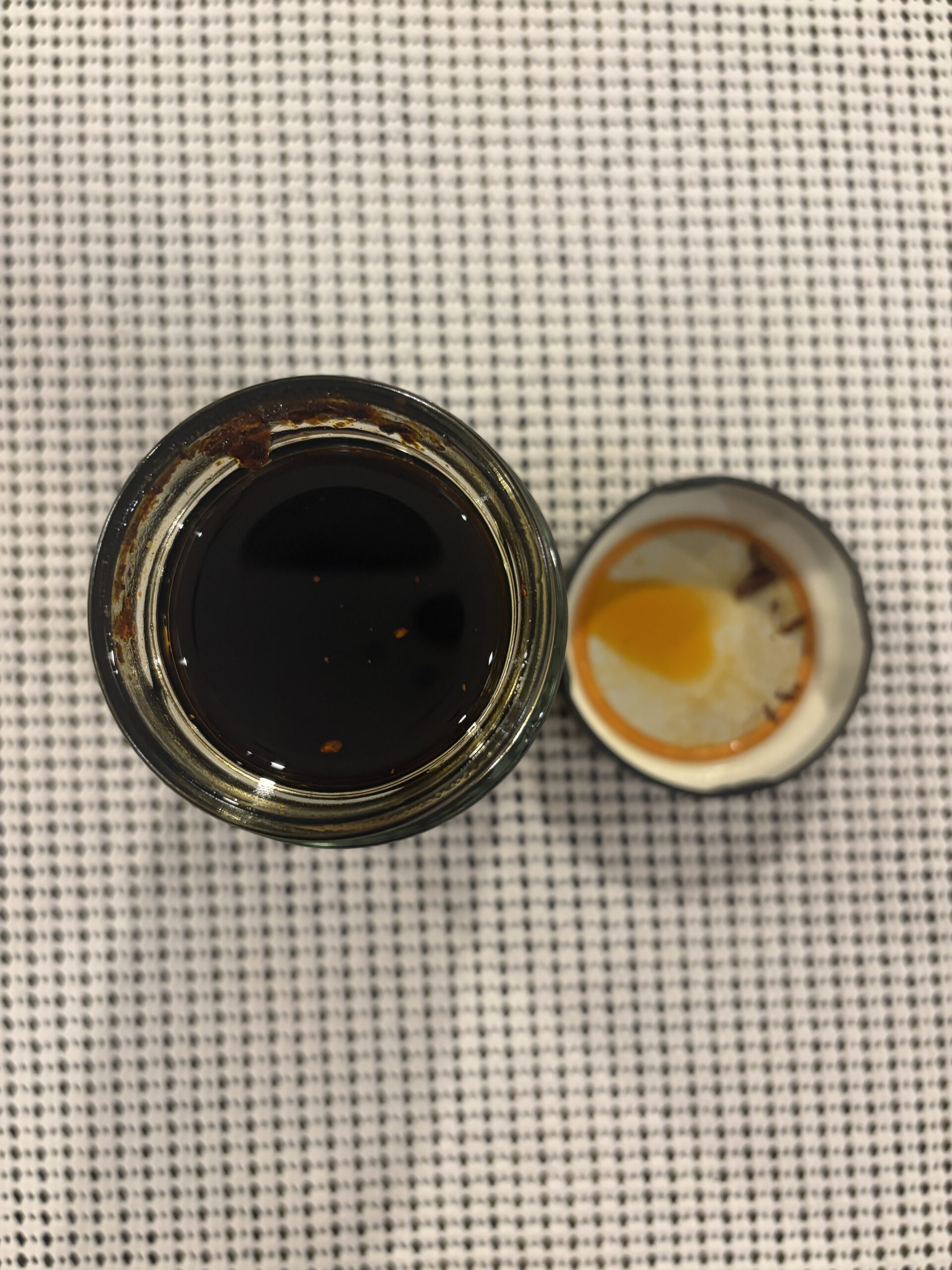 Fly By Jing Xtra Spicy chili crisp open jar showing thick oil and Sichuan peppercorn bits — Flavor Index Lab