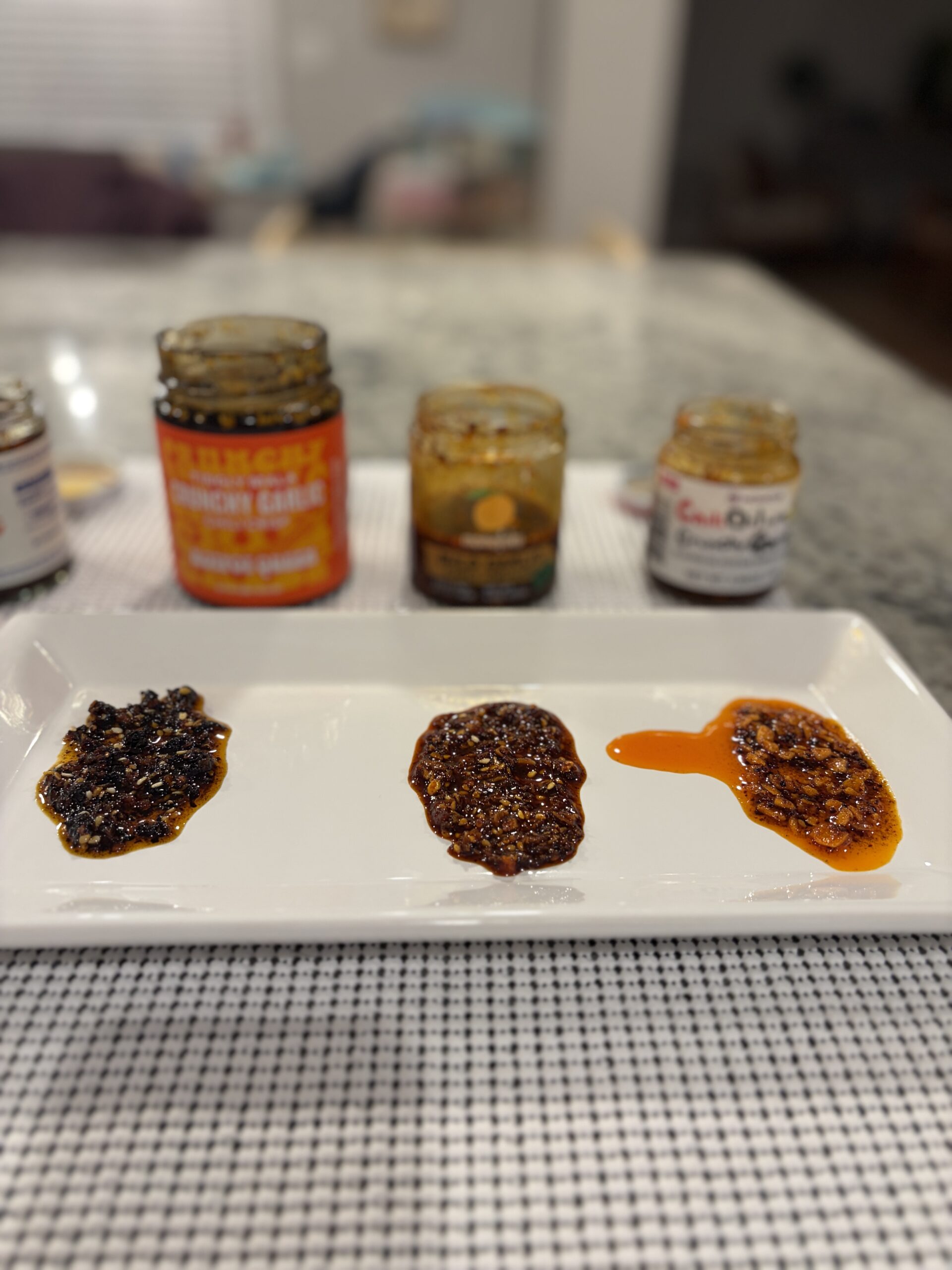 Mama Teav's, Momoya, and Hotpot Queen garlic chili crisps plated for comparison — Flavor Index Lab