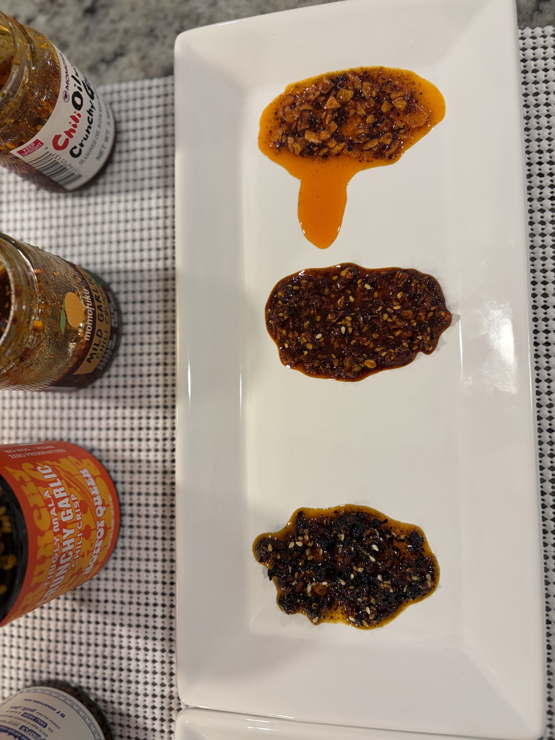 Top-down view of Mama Teav's, Momoya, and Hotpot Queen garlic chili crisps showing garlic visibility differences — Flavor Index Lab