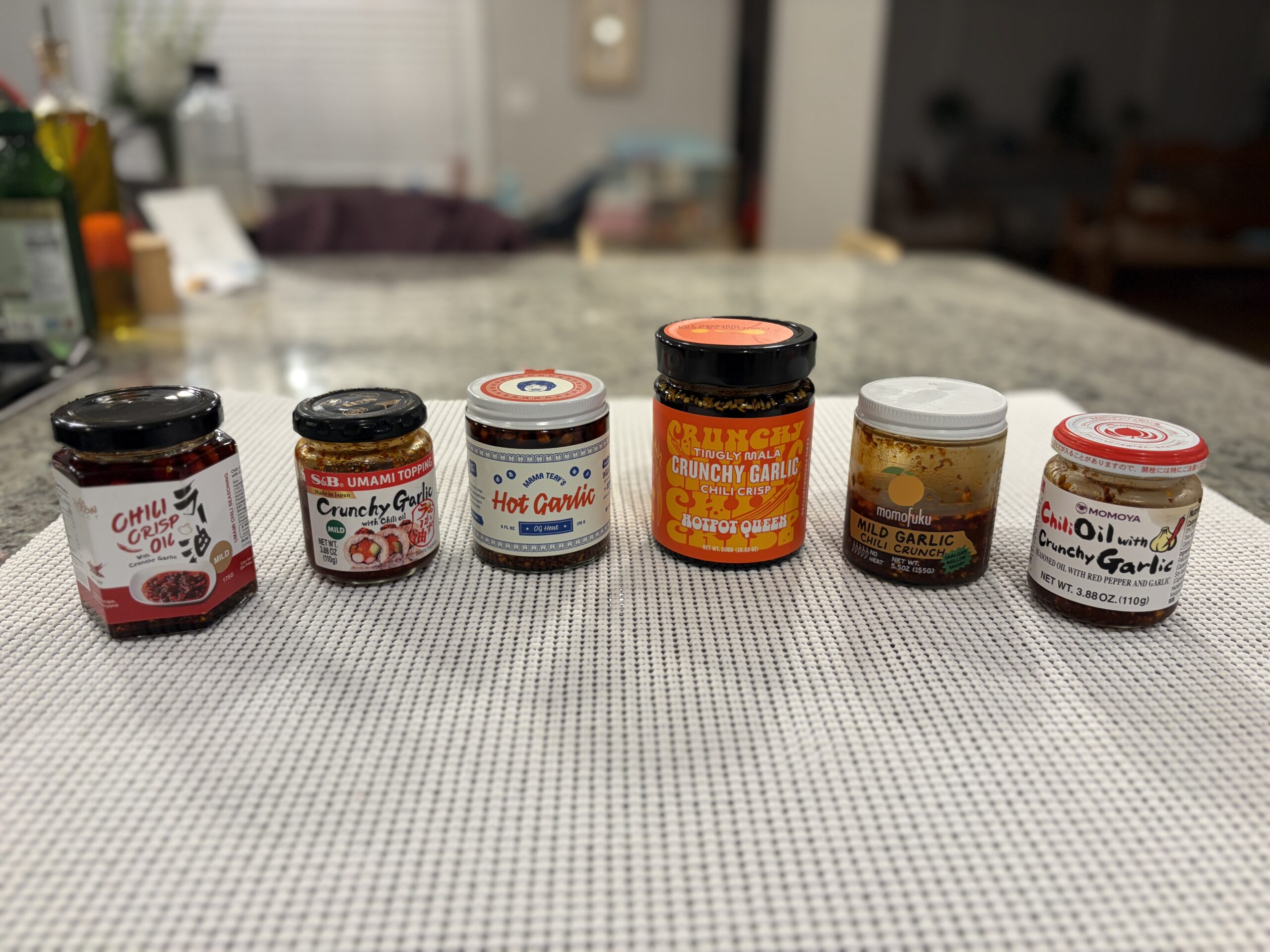 Six crunchy garlic chili crisp jars lined up for comparison — Flavor Index Lab
