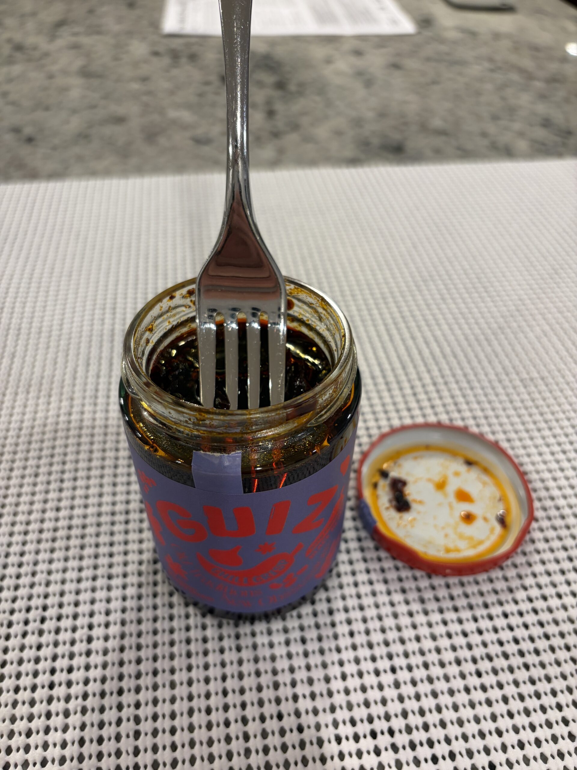 Fork resting on GUIZ black bean chili crisp solids without sinking — Flavor Index Lab