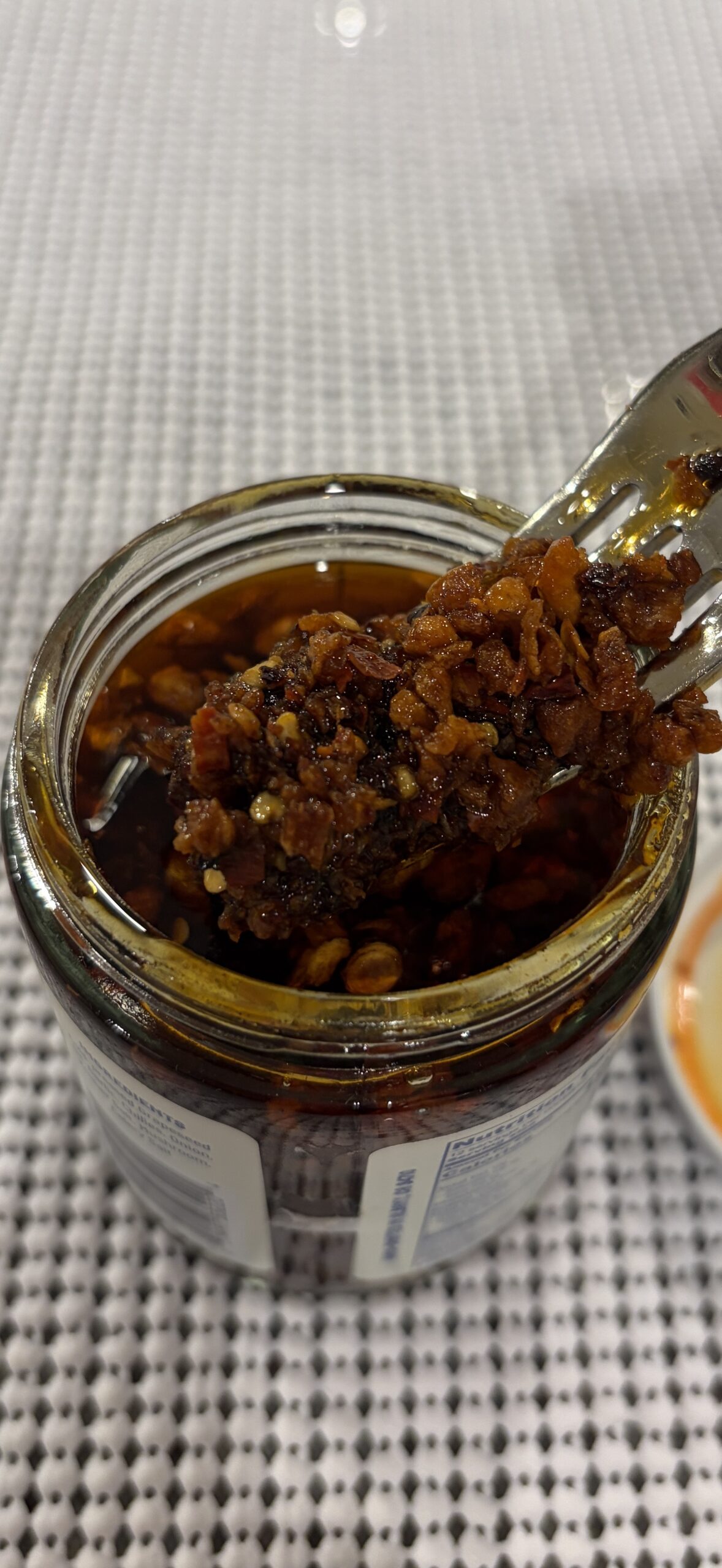 Mama Teav's chili crisp fork pull with thick garlic bits and oil draining — Flavor Index Lab