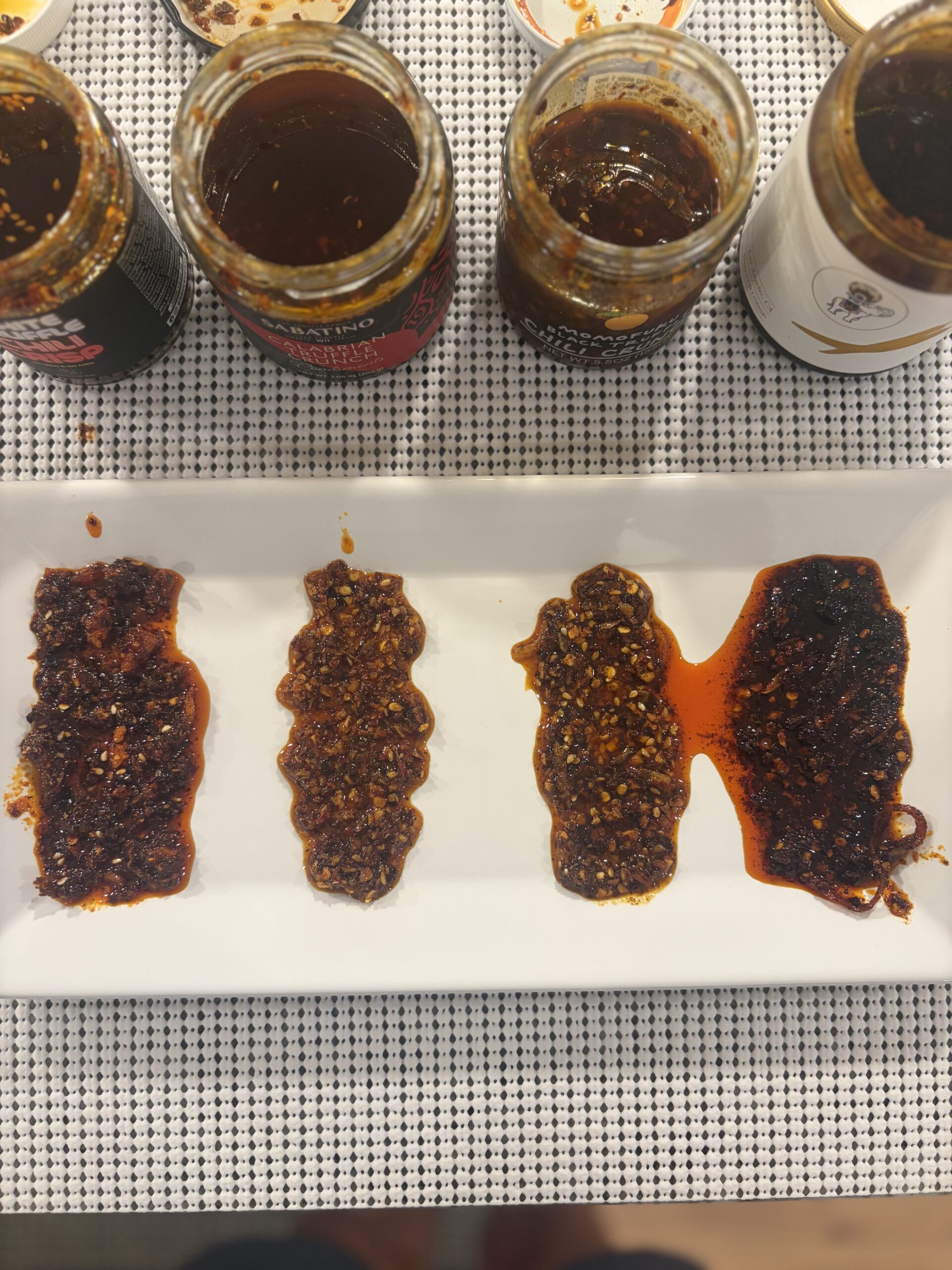 Close-up of Sabatino, Sauce Up, Momofuku, and White Elephant truffle chili crisps on plate — Flavor Index Lab