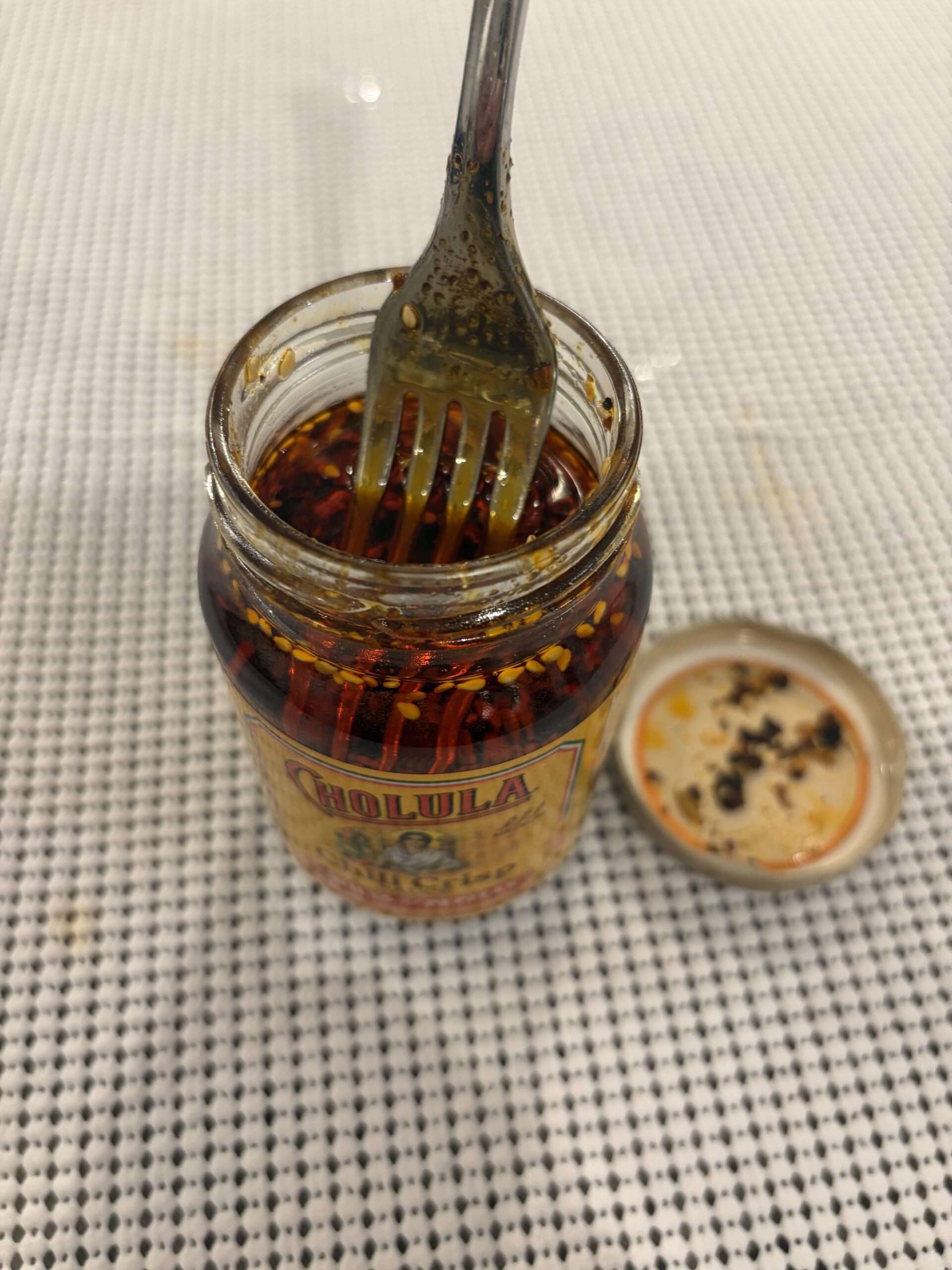 Fork resting on Cholula chili crisp solids before stirring — Flavor Index Lab