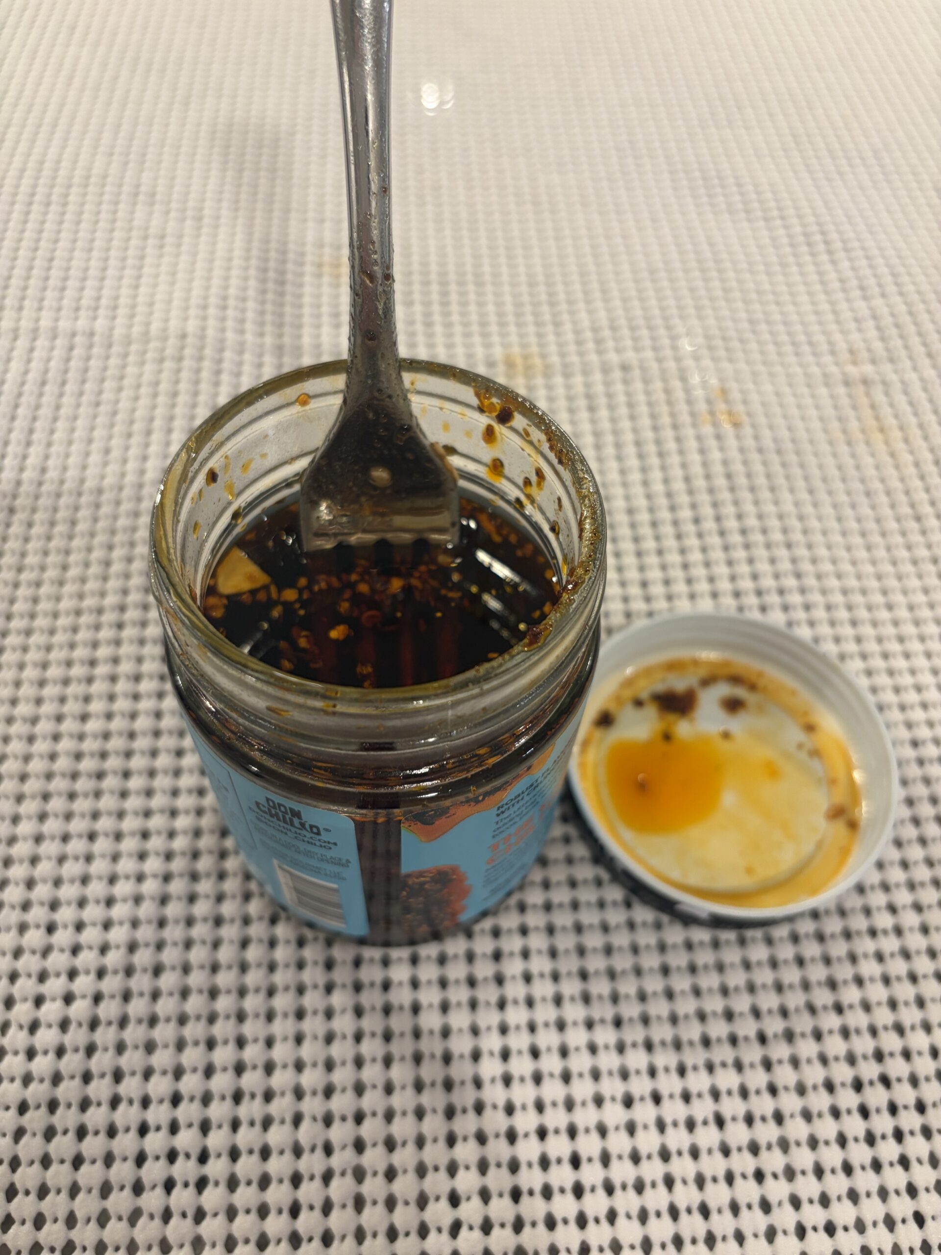 Fork resting on Don Chilio Chipotle Salsa Macha solids before stirring . Flavor Index Lab