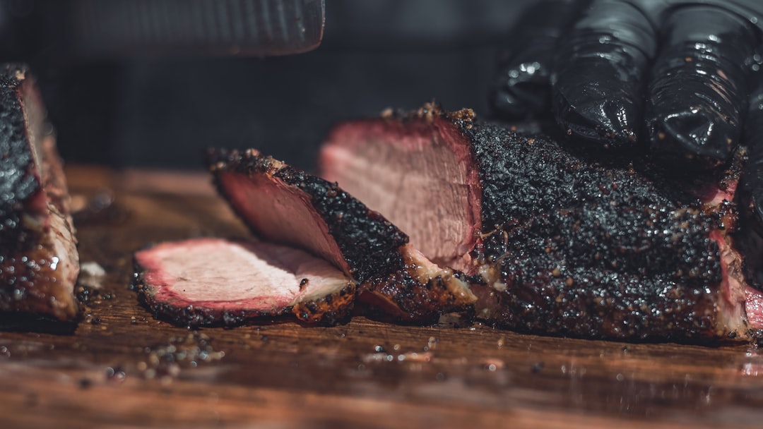 Sliced smoked brisket with peppercorn bark on a cutting board — Flavor Index Lab