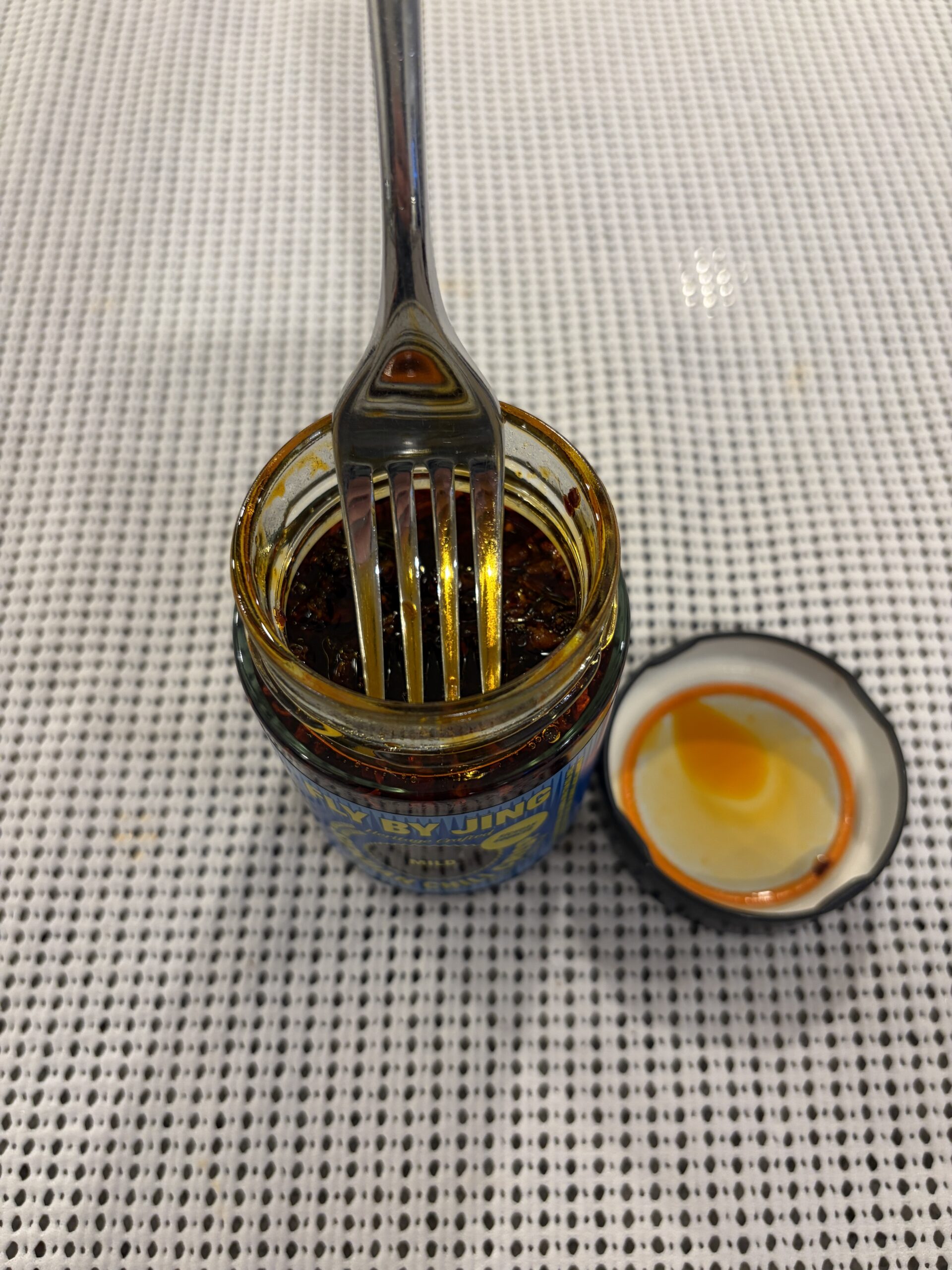 Fork resting on Fly By Jing Mild chili crisp solids without sinking — Flavor Index Lab