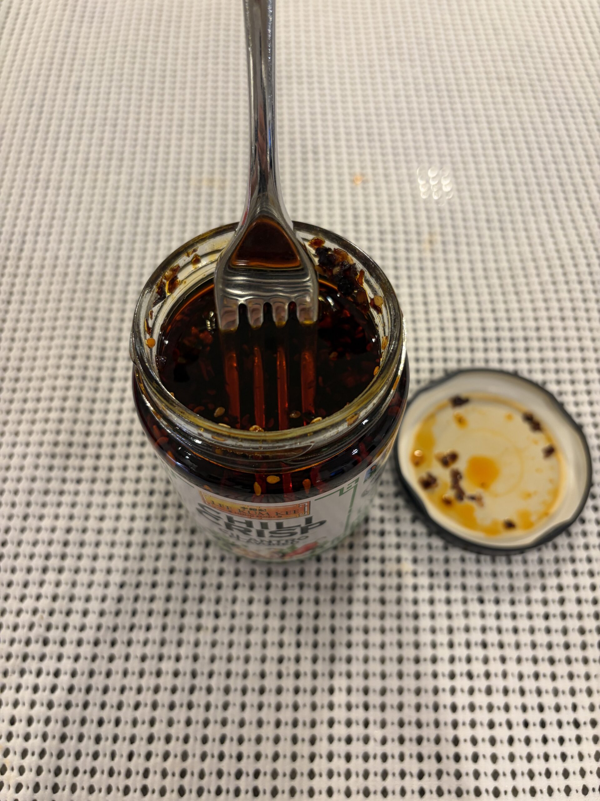 Fork resting in Lee Kum Kee cilantro chili crisp paste — Flavor Index Lab